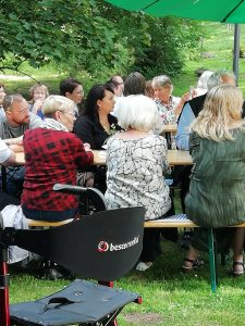 Gäste des Sommerfestes sitzen auf den Bänken im Park Hohenrode in Nordhausen